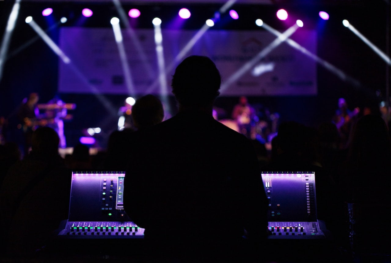 Image depict a silhouette in front of a switchboard during a concert. Used as a cover image for an overview of the Royal NFT streaming music royalty investing platform.