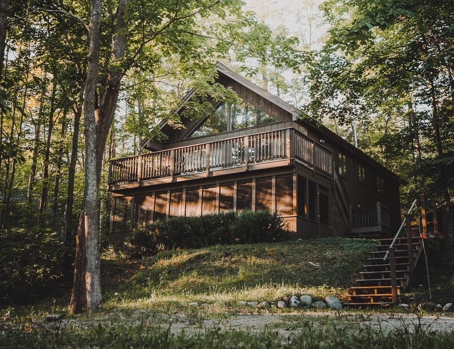 Depicts a wooden cabin in the woods. Used as a cover image for an article on Arrived Homes vs Here, which compares these two fractional real estate investing platforms for short term vacation rentals.
