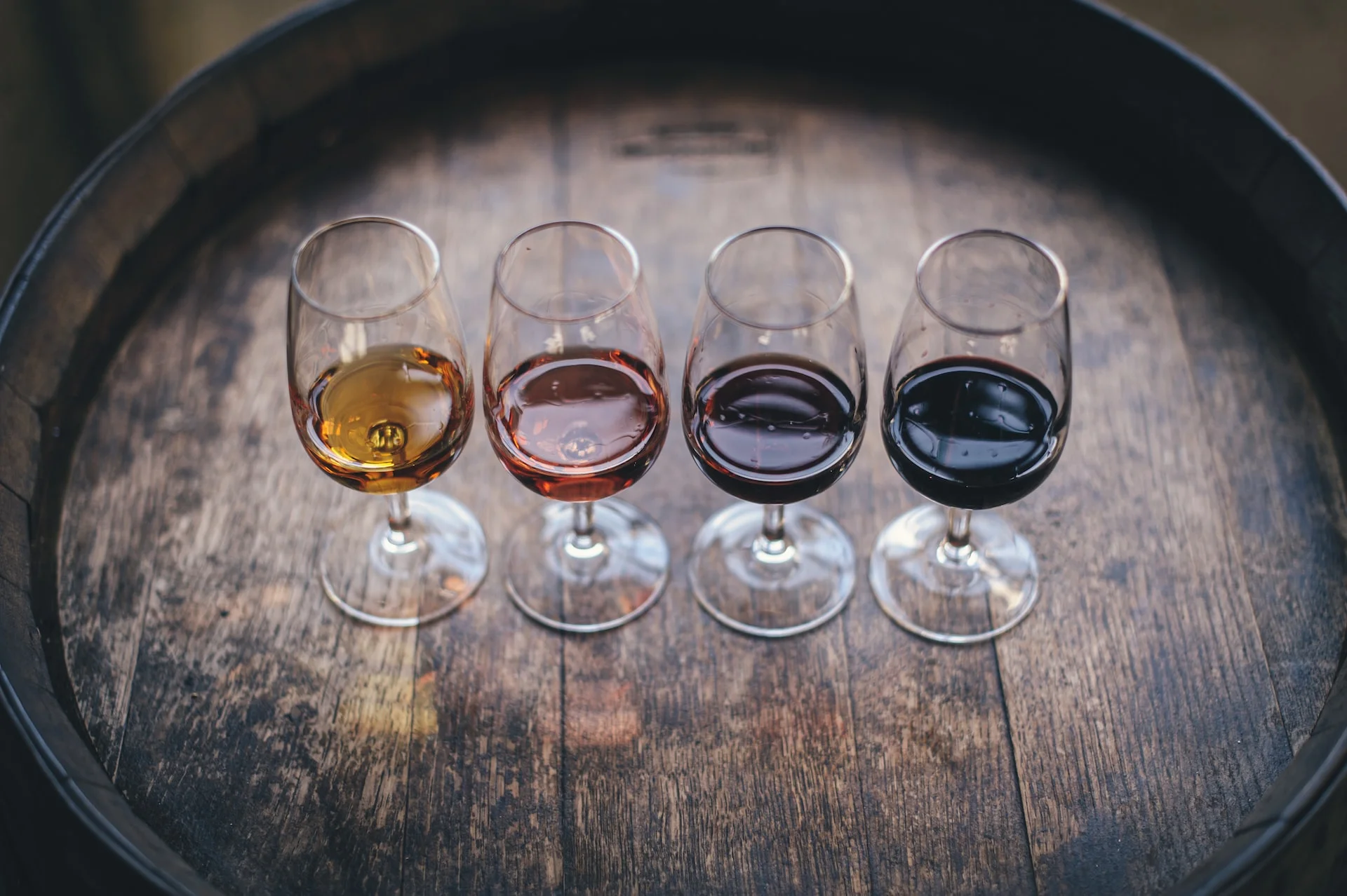 Several different wine glasses placed side-by-side. Used as a cover image for an article comparing wine investment platforms Vint and Vinovest.