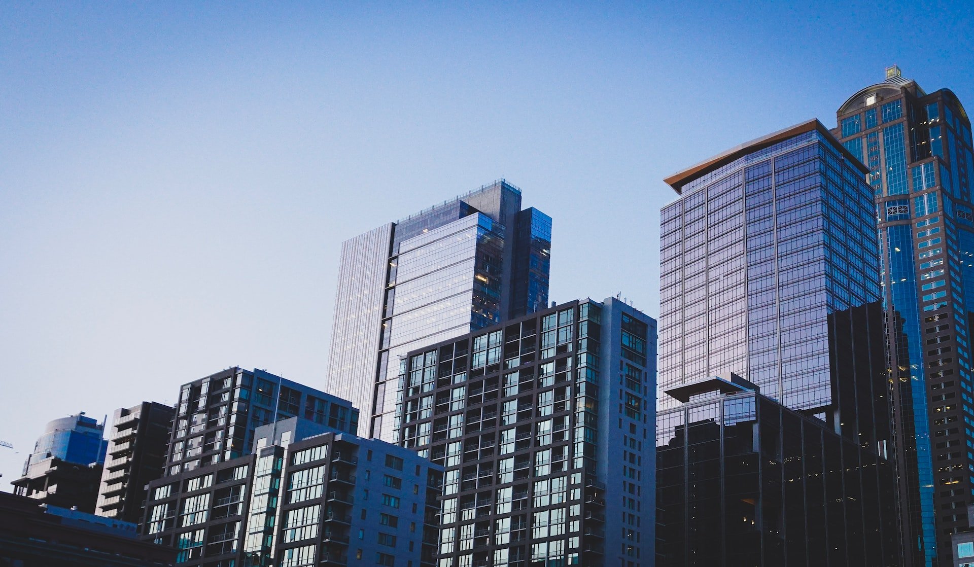 Depicts an upward view of several high rise builds. Cover photo for a landing page about the real estate asset class.