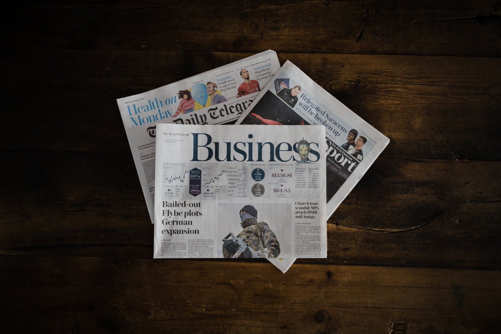 Depicts three newspapers displayed on a table. Used as a cover photo in an article discussing news in alternative investments from April 2023.