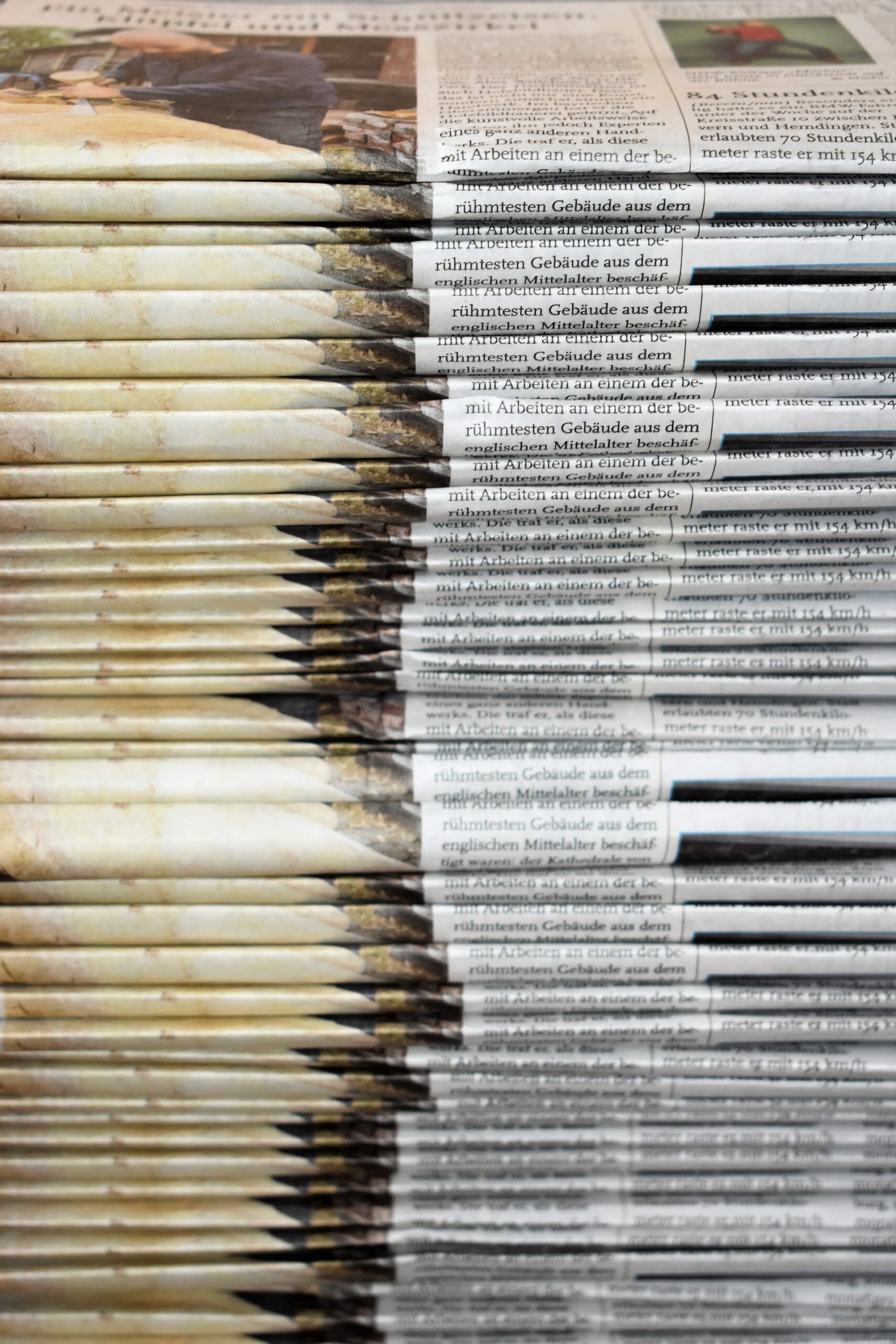 Depicts a stack of newspapers. Used as a cover image for an article about alternative investing news in May 2023.