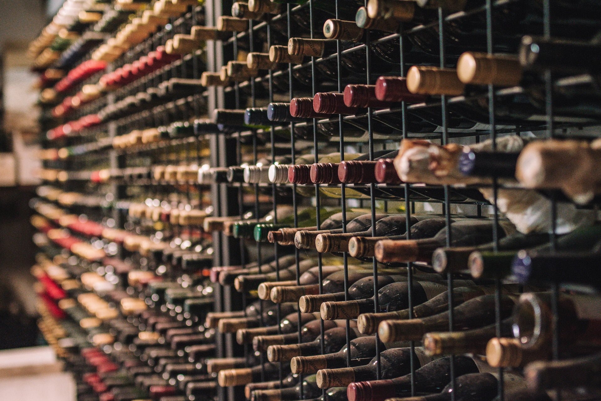Depicts a series of wine bottles arranged in storage shelves. Used as a cover image for a landing page introducing Vint, a fractional investment platform for Wine and Whisky.