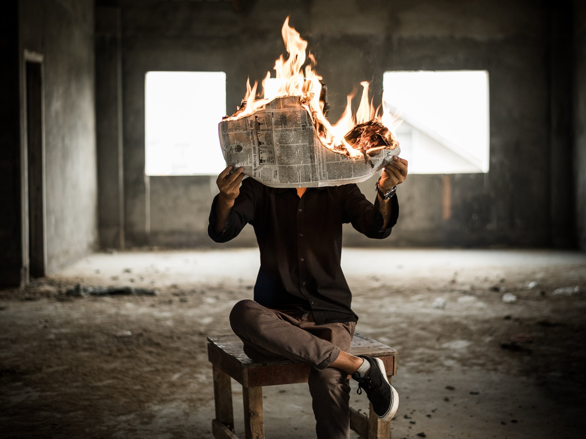 Depicts a person holding a burning newspaper. Used as a cover image for alternative investment news from the week of July 24th.