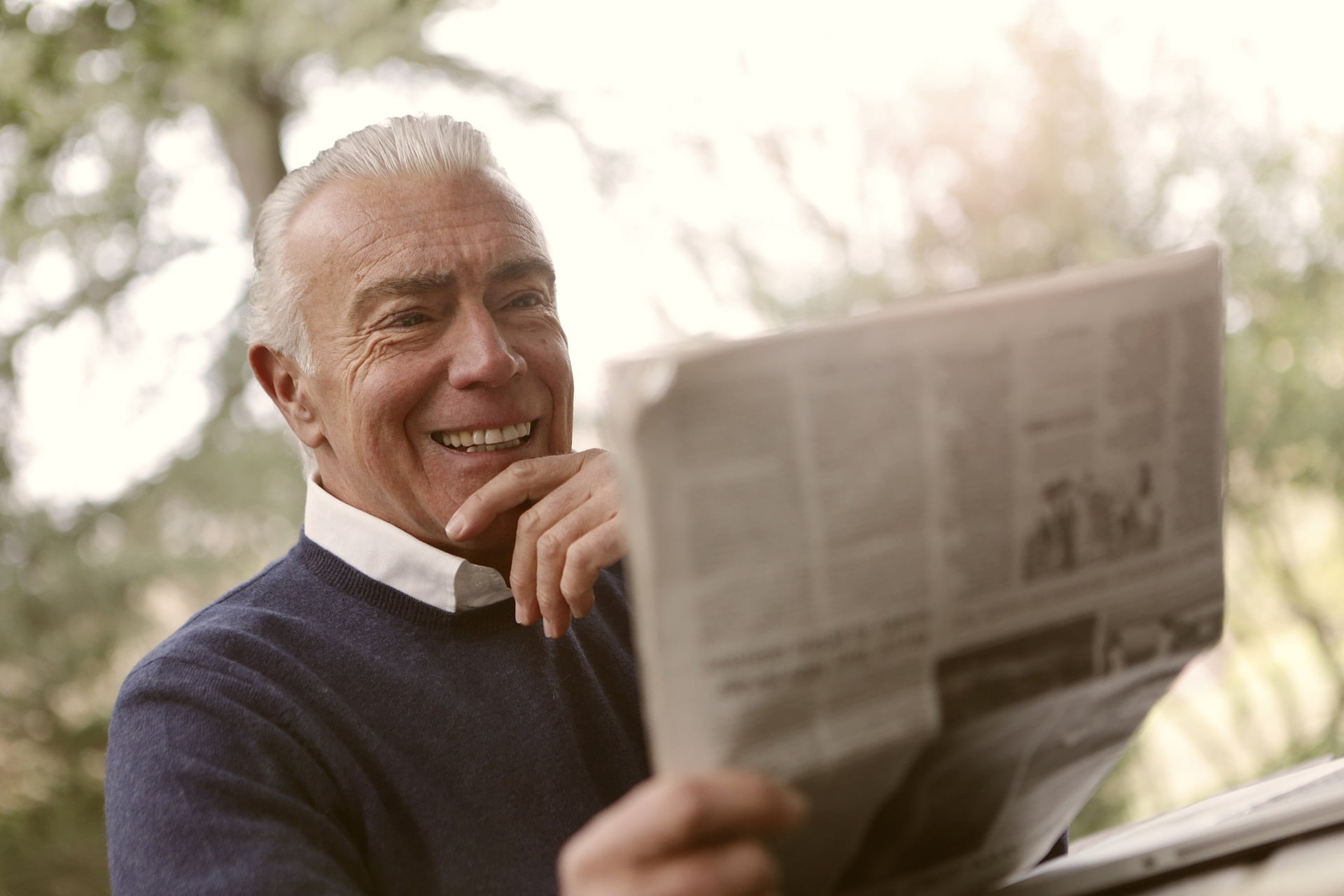 Depicts a man reading a newspaper outside. Used as a cover image for a roundup of alternative investment news.
